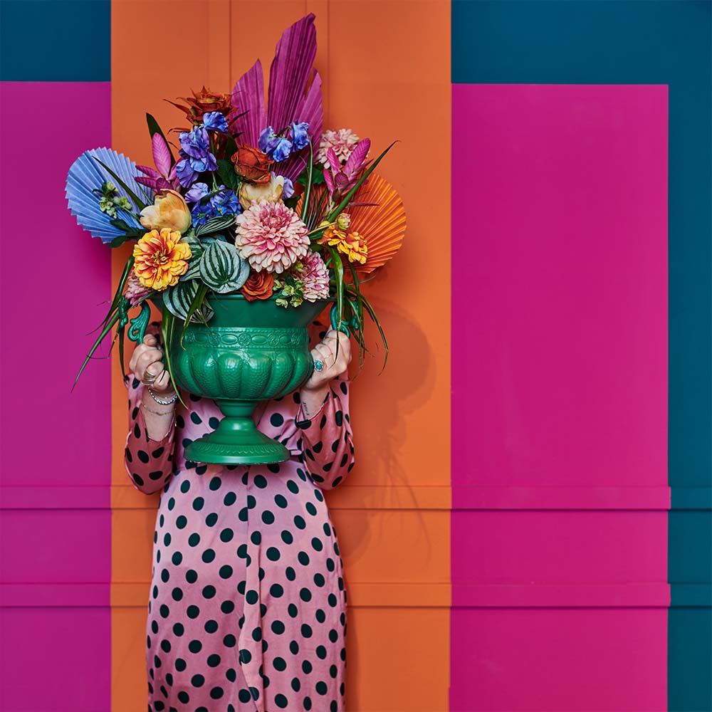 Lady with flowerpot containing artificial flowers on a colourful background